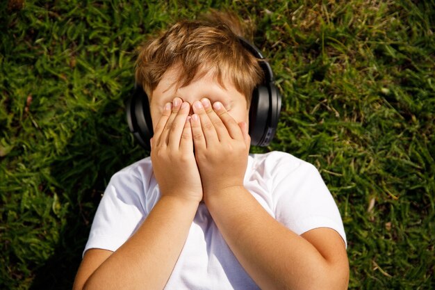 Handsome boy with headphones listening to music lying on the grass