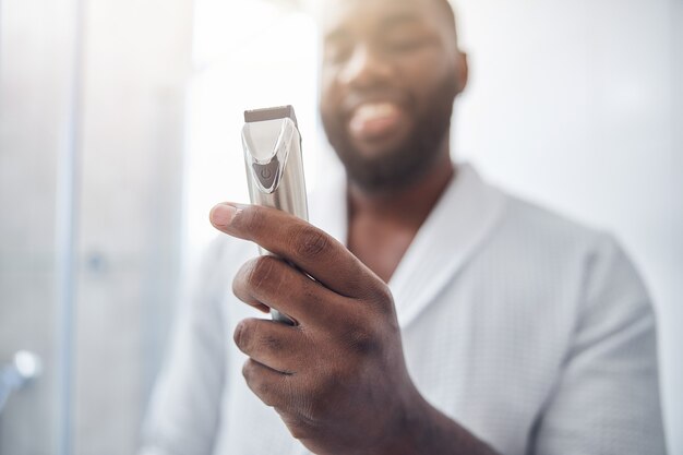 Handsome brunette male person keeping smile on his face while going to do correction of his beard