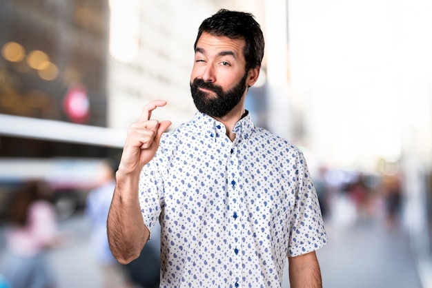 Handsome brunette man with beard making tiny sign