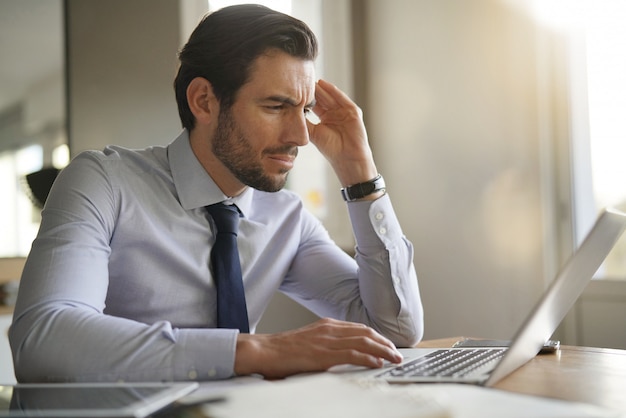 Handsome businessman concentrating on laptop in modern office 