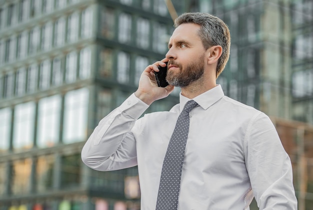 Handsome businessman having smartphone call in the street businessman call on smartphone