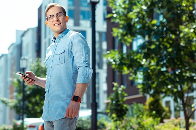 Handsome businessman holding smartphone while standing outside