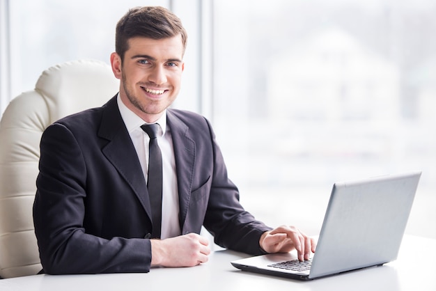 Handsome businessman is working with laptop in office.