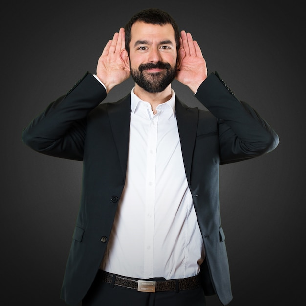 Handsome businessman listening something on black background