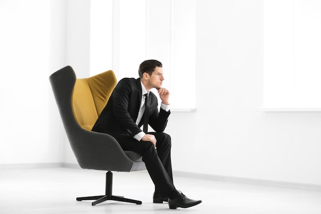 Handsome businessman sitting in comfortable armchair indoors