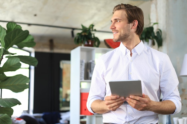 Handsome businessman using his tablet in the office.