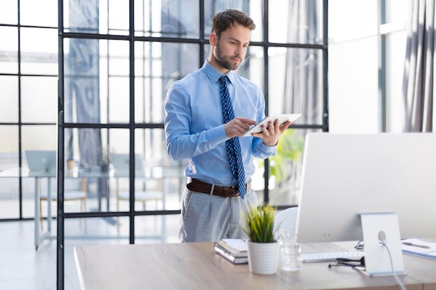 Handsome businessman using his tablet in the office