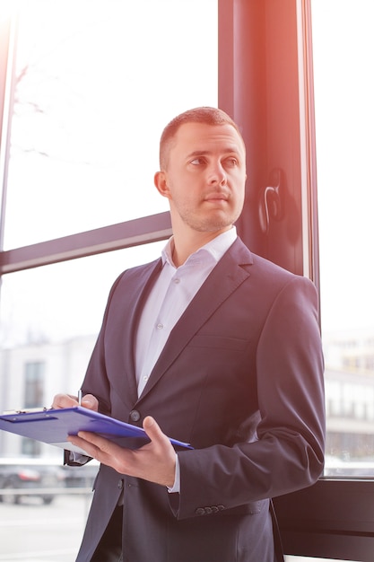 Handsome businessman wearing a black suit with a clipboard