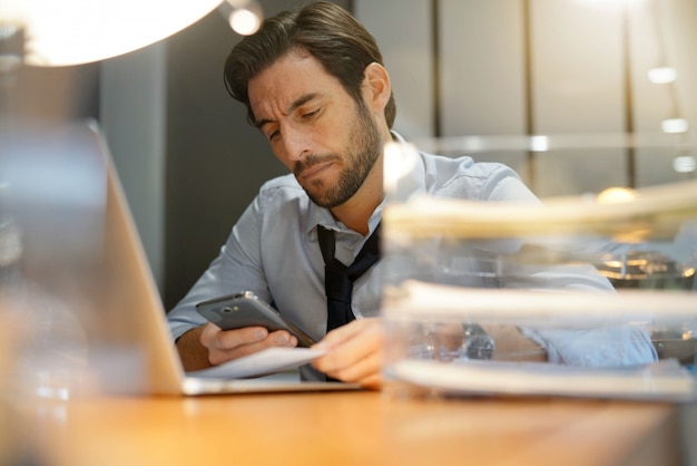 Handsome businessman working late checking cellphone in modern office