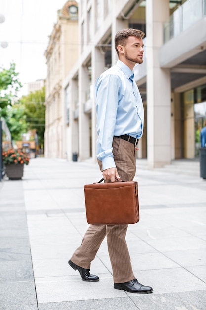 Handsome Caucasian businessman walks with briefcase on the of the city.