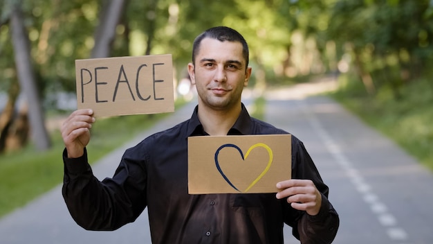 Photo handsome caucasian man adult businessman patriot guy stands in park outdoors holds two banners