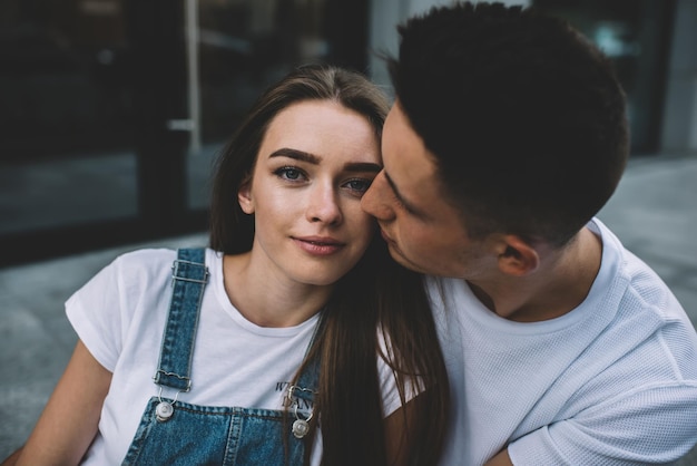 handsome Caucasian man dressed in casual wear taking rest at urban setting with cute young wife