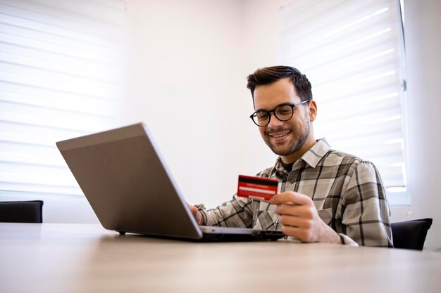 Handsome caucasian man using his laptop computer and credit card for ebanking or purchasing online