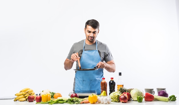 Handsome cheerful smiling indian man preparing meal in the kitchen,  Healthy food, cooking concept.