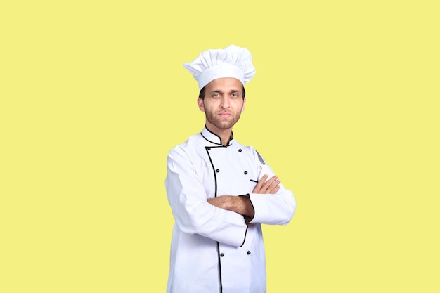 handsome chef cook crossed arms over yellow background indian pakistani model