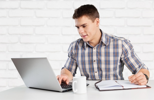 Handsome college student using his laptop computer in the campus