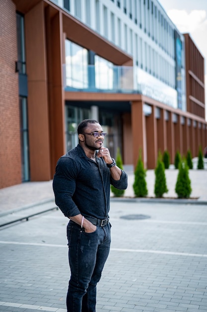 Handsome confident businessman standing outside. Office manager in glasess in urban city.