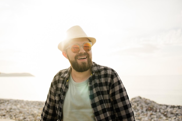 Handsome and confident Outdoor portrait of smiling man wearing hat and sunglasses on beach empty space for text Holidays travel and summer tourism