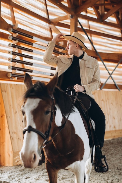 Handsome cowboy man riding a horse on a ranch