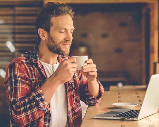 Handsome designer is enjoying the aroma of coffee.