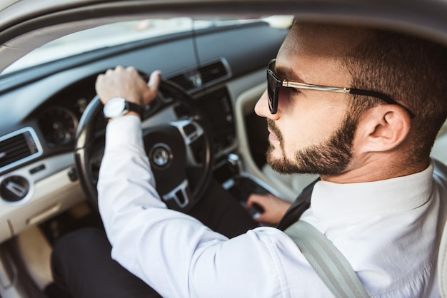 Handsome driver in sunglasses driving car