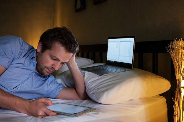 Handsome entrepreneur man browsing internet in bed at night