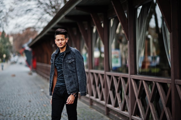 Handsome and fashionable indian man in black jeans jacket posed outdoor