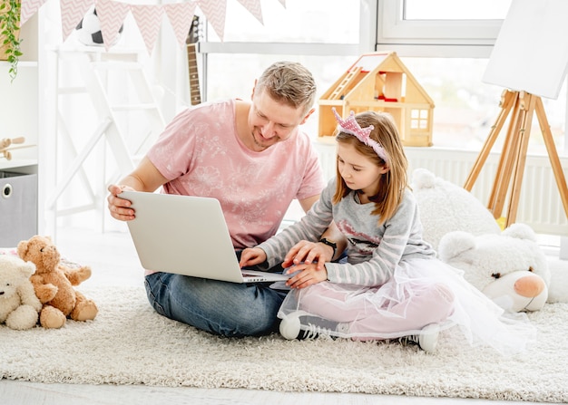 Handsome father teaching daughter on laptop