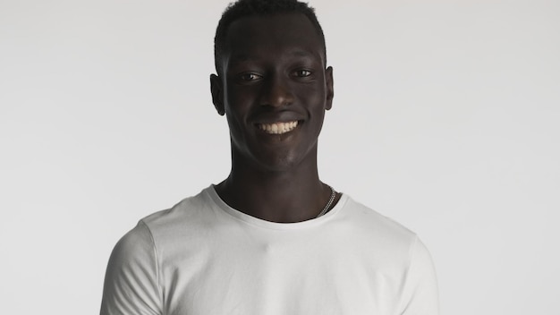 Handsome friendly African American guy in white t-shirt looking happy over white background. Joyful man