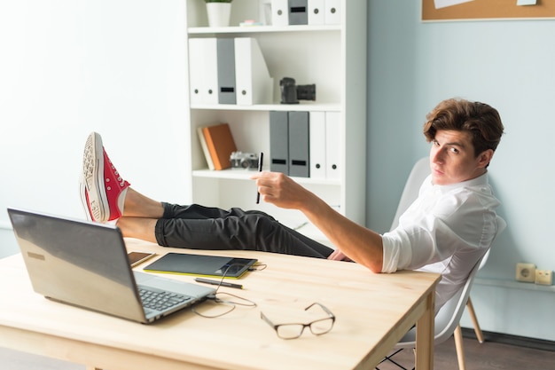 Handsome funny man in white shirt has a rest sitting at the office