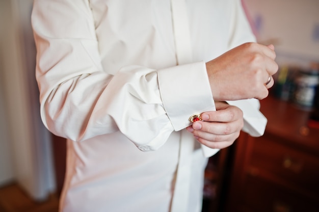 Handsome groom dressing up and getting ready for his wedding ceremony.