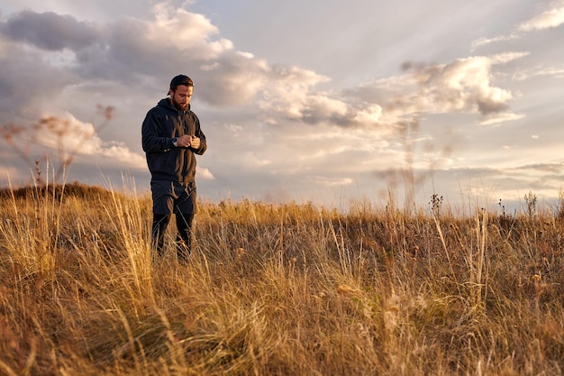 Handsome guy in black wear having rest outdoors, in nature. Male after sport, enjoy the rest. Relaxed man jogger, leisure after training. outdoor portrait. at sunset in nature in countryside