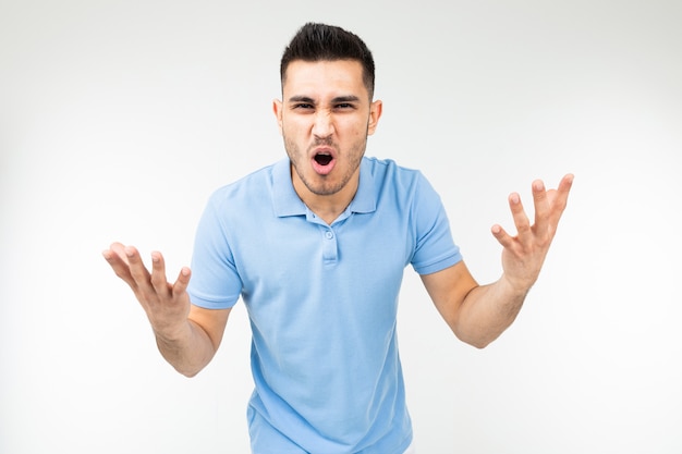 Handsome guy in a blue t-shirt screaming at the camera on a white isolated