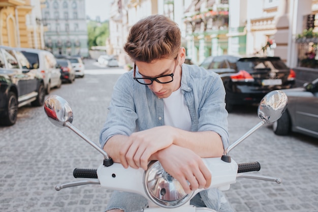 Handsome guy is sitting on motorcycle and looking down