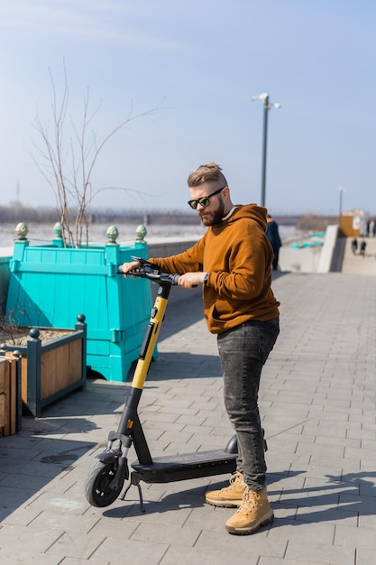 Handsome guy man riding on electric urban modern scooter eco transport technology concept