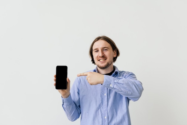 Handsome guy pointing finger at empty screen phone on white background