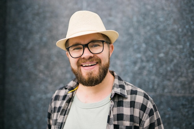 Handsome guy tourist looking happy wearing straw hat for travelling standing against concrete wall background with copy space