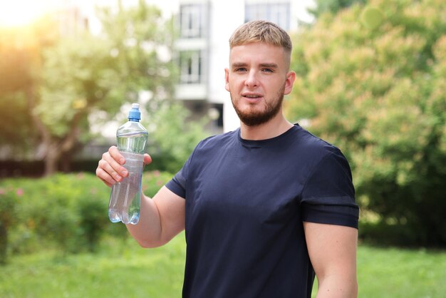 handsome guy young happy thirsty man runner is drinking pure fresh water from plastic bottle