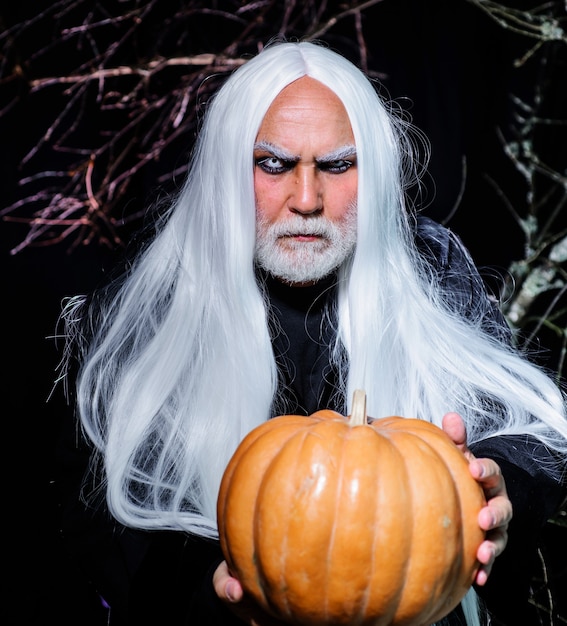 Handsome Halloween man with pumpkin in hand. Devil man. Male in witch costume ready to Halloween party.