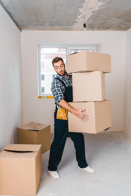 Handsome handyman holding boxes while standing in room