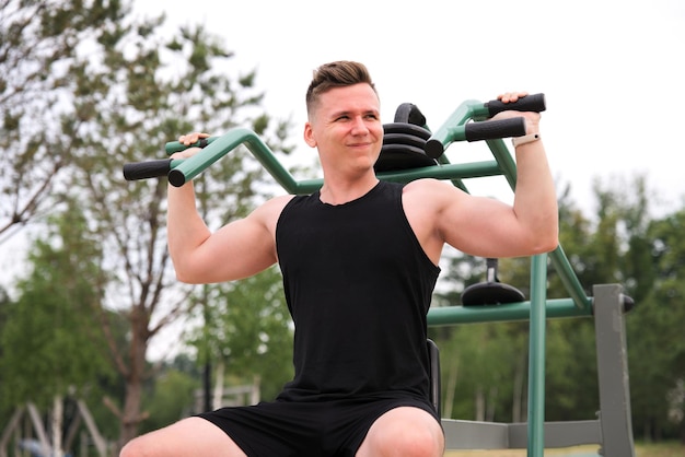 handsome happy strong athletic man athlete bodybuilder training outdoors at open air gym