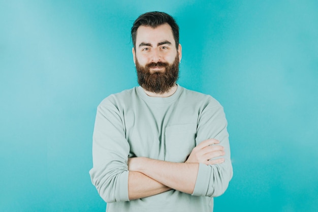 Photo handsome hipster bearded crossing arms while looking confident to camera young man happy blue tone color background expression of normal people mockup concept with people