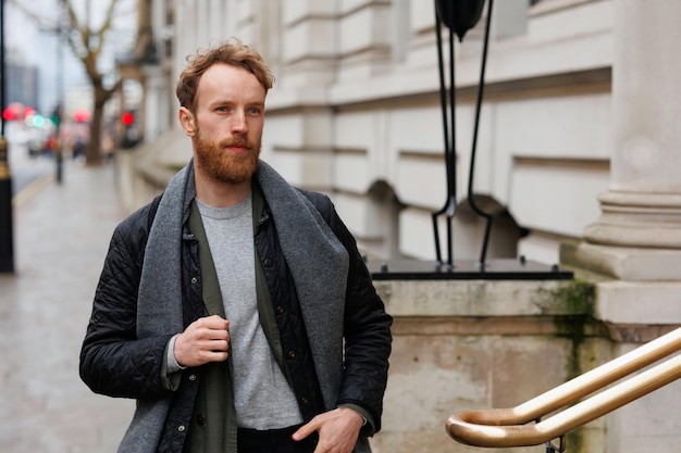 Handsome hipster man in stylish clothes walking down the street of London