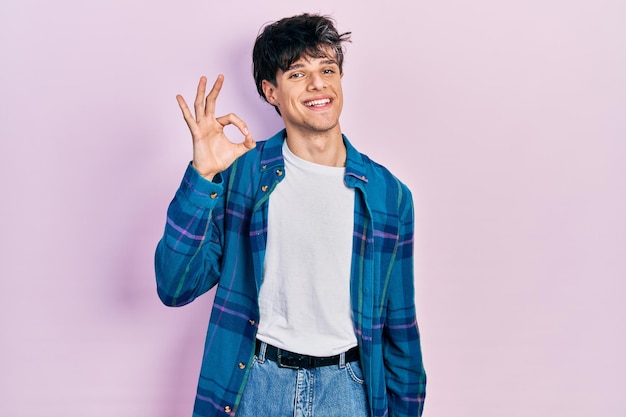 Handsome hipster young man wearing casual white t shirt and vintage shirt smiling positive doing ok sign with hand and fingers successful expression