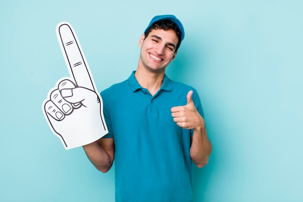 Handsome hispanic man feeling proudsmiling positively with thumbs up number one hand fan concept