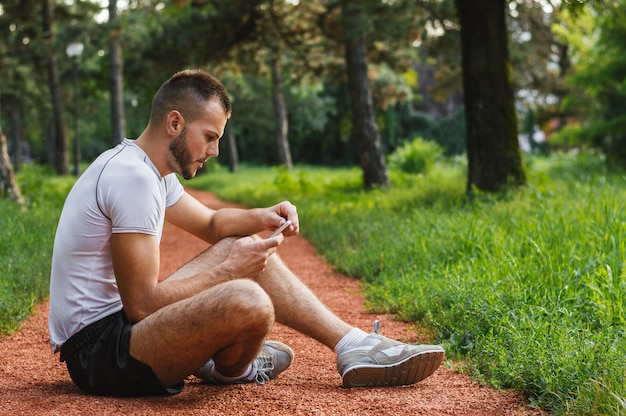 Handsome jogger browsing Internet using his smart phone