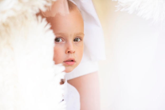 A handsome little boy peeps out The big eyes of the child look into the camera