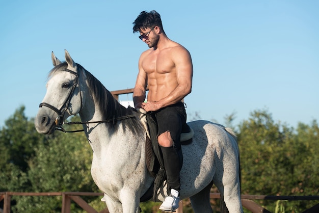 Handsome Macho Man Cowboy Riding on a Horse  Background of Sky and Mountains