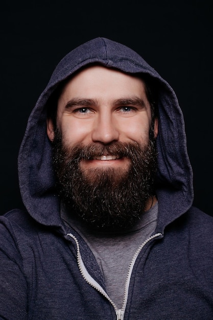 Handsome male big beard in hoodies studio shot on black background looking directly at the camera