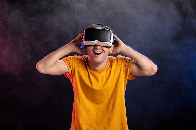 Handsome male wearing virtual reality headset on dark surface